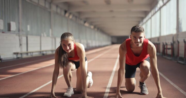 Free Men and Woman in Red Tank Top is Ready to Run on Track Field Stock Photo